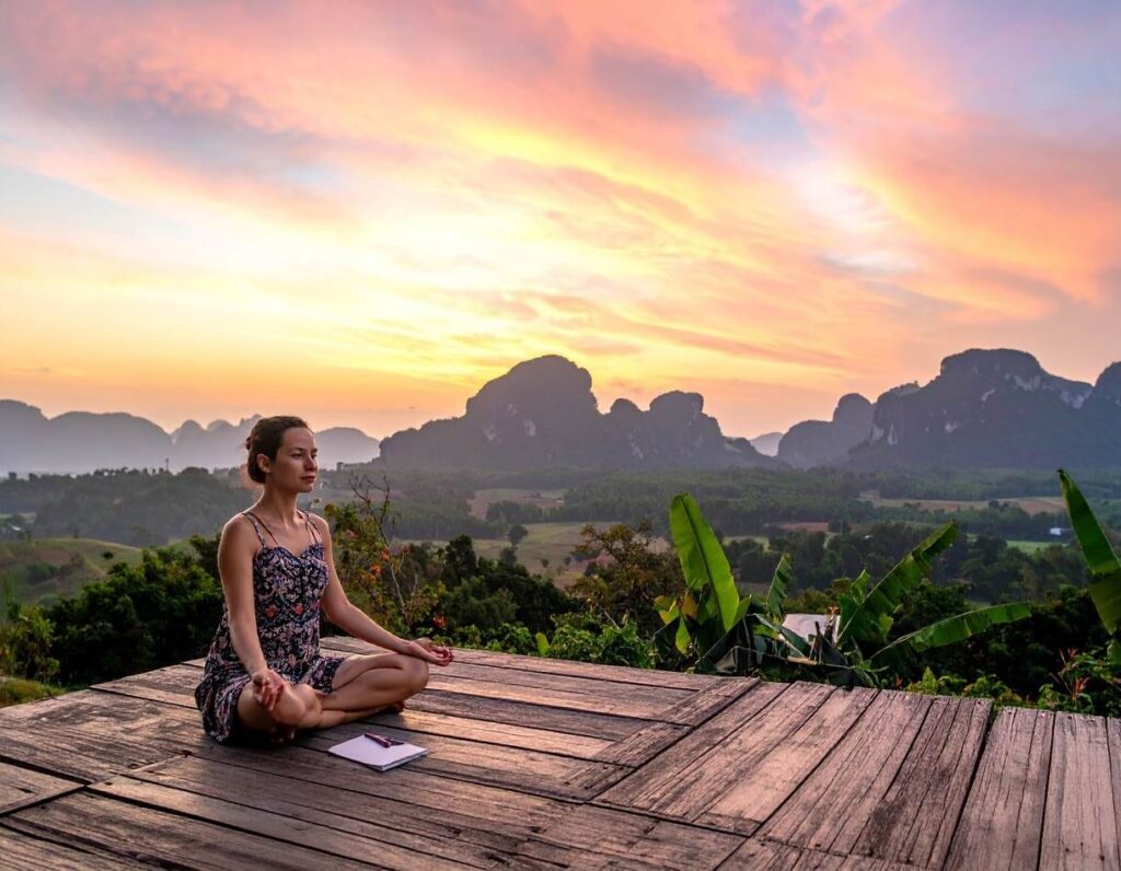 Practitioner meditating at sunset in natural landscape