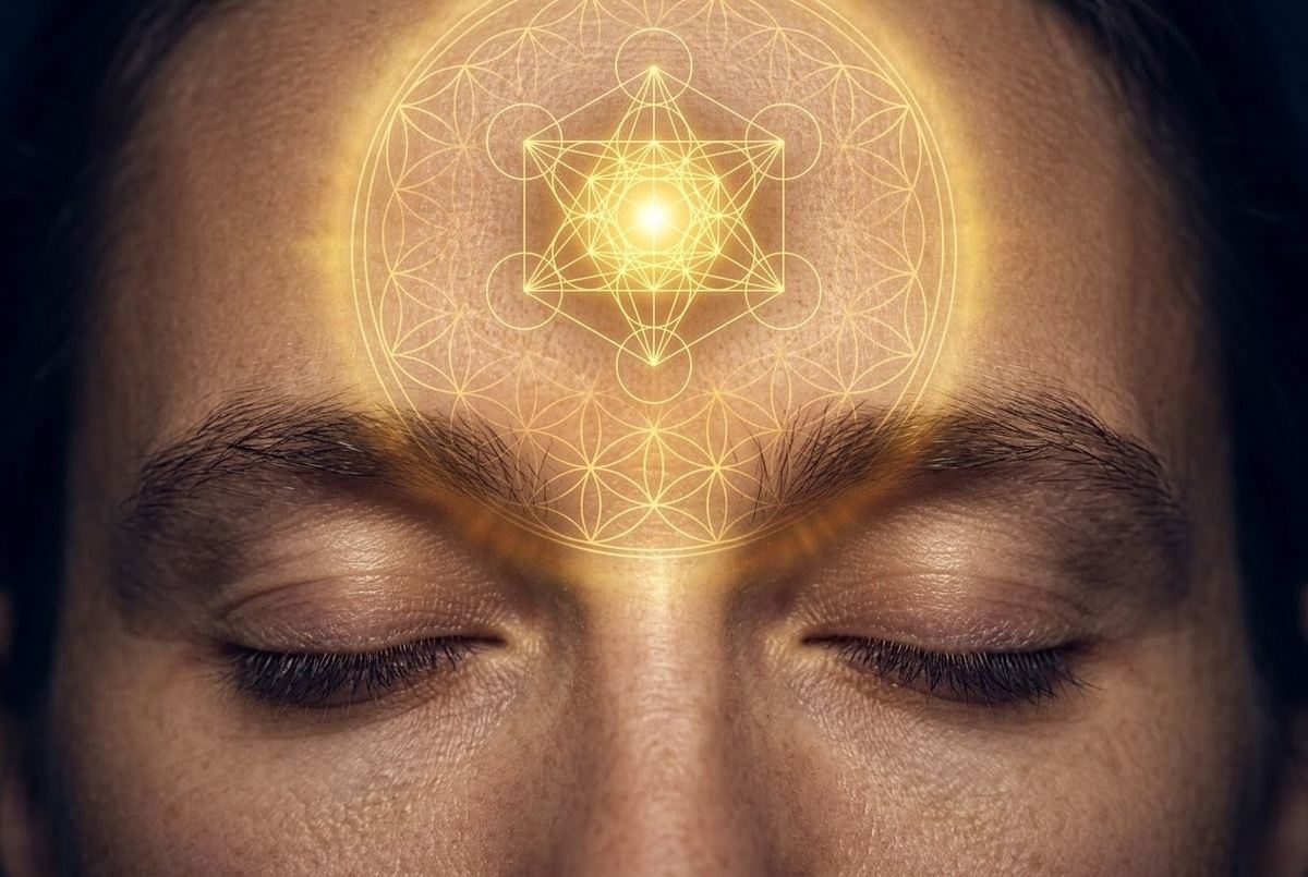 Photorealistic image of human head with glowing golden third eye and sacred geometry overlay