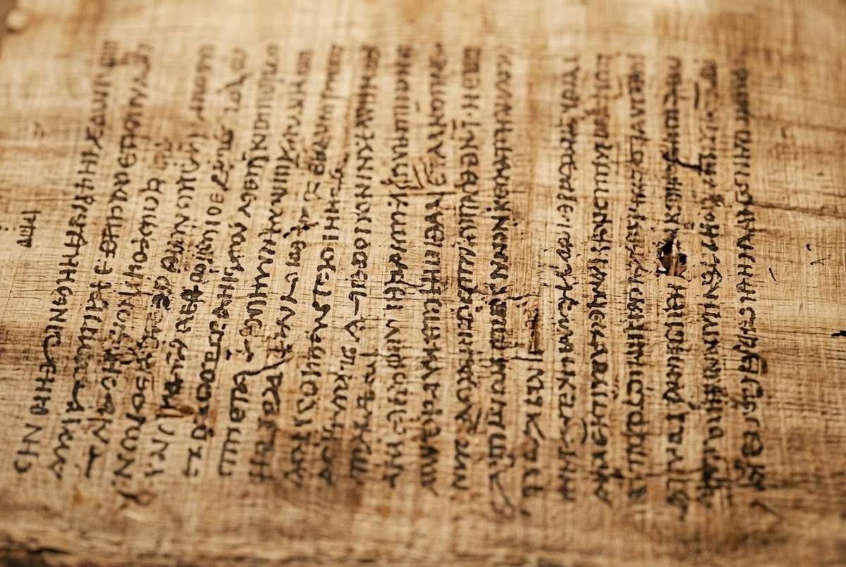 Close-up of ancient papyrus showing condensed Coptic text with minimal marginalia