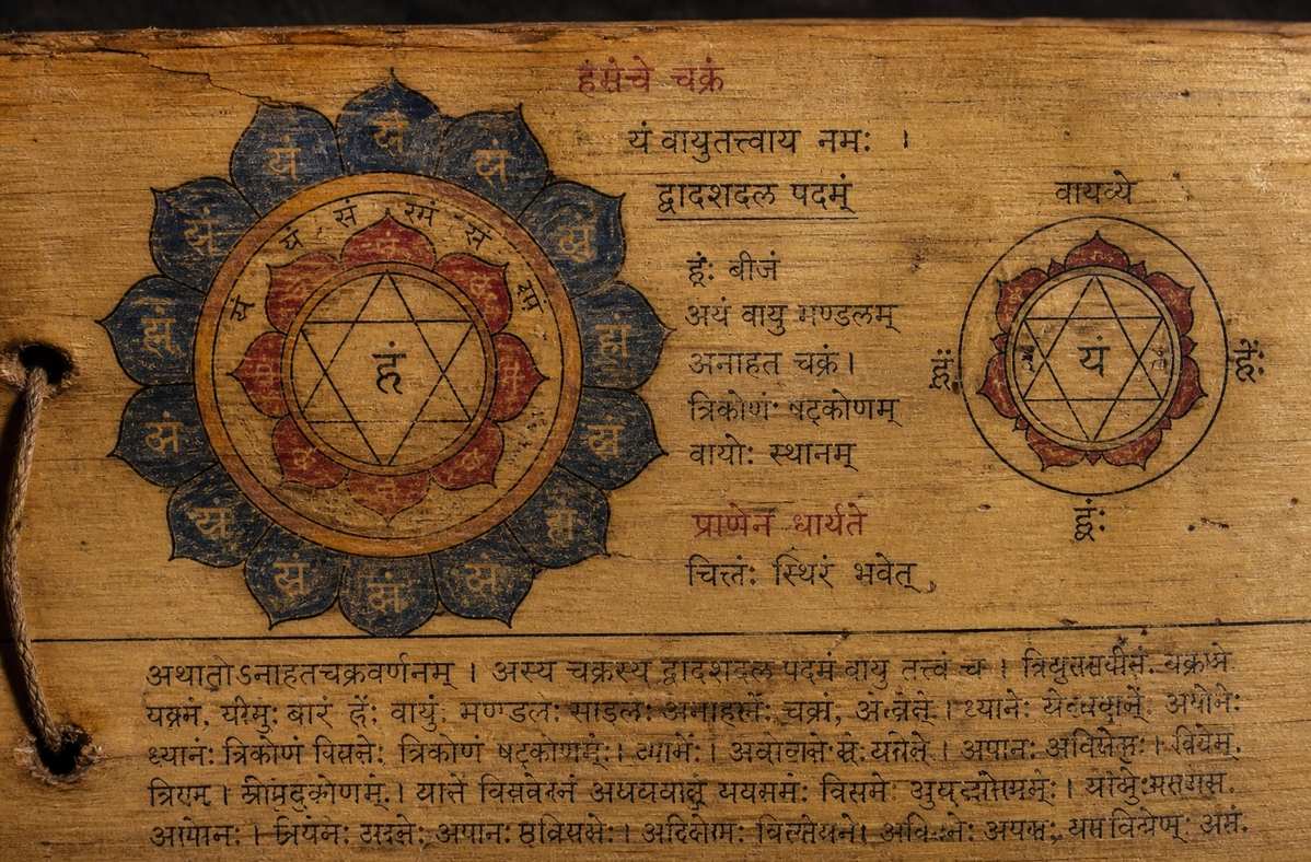 An ancient Tantric manuscript page showing hand-drawn chakra diagrams with Sanskrit annotations and deity illustrations