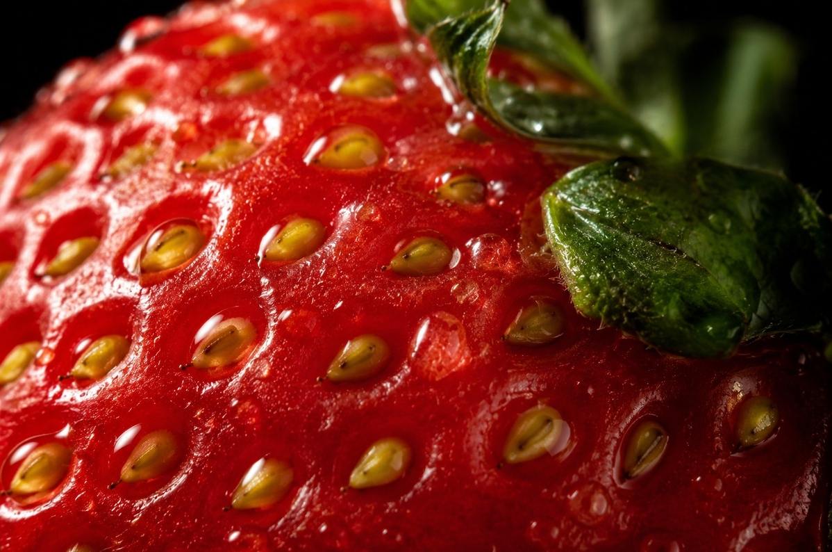Extreme macro photograph of strawberry seeds and flesh with dramatic lighting