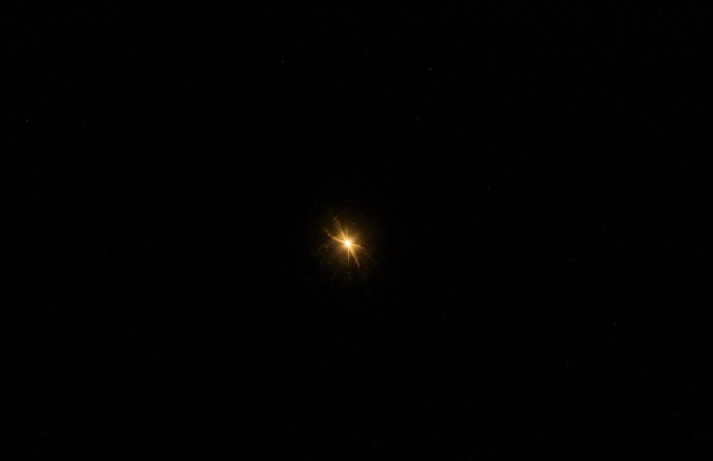 Single luminous golden spark floating in vast empty darkness searching for connection